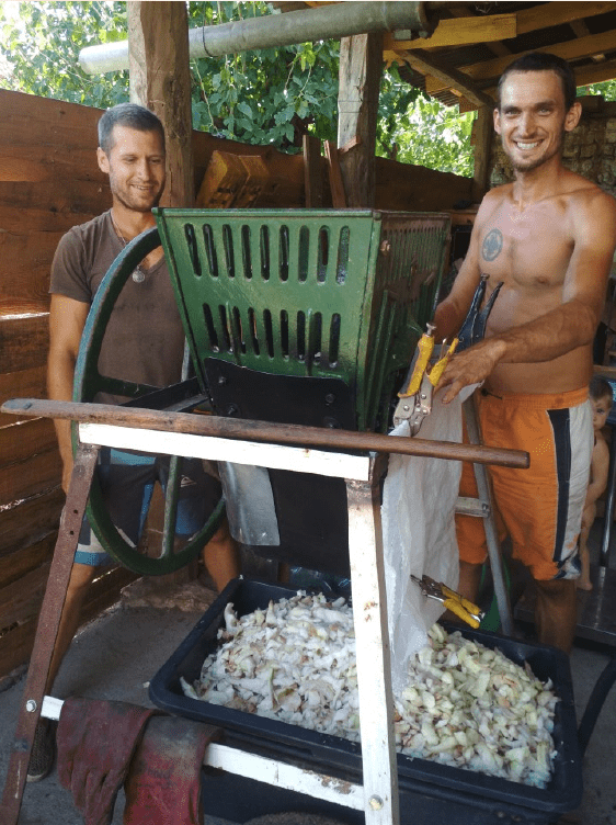 2 junge Männer stehen hinter einer manuellen Hackschnitzelmaschine für zum Beispiel Zuckerrüben